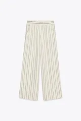 Pantalón de lino color crudo con rayas verticales negras y lentejuelas. Tiro alto con cintura elástica y bolsillos laterales.