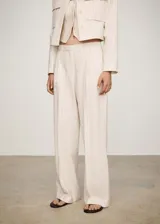 Pantalón de tiro medio color crema a rayas verticales finas, con dos bolsillos delanteros, cierre oculto de botón, gancho y cremallera, diseño recto y largo.