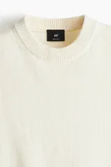 Chaleco de punto color crema con cuello redondo y ribete acanalado en cuello, sisas y bajo.