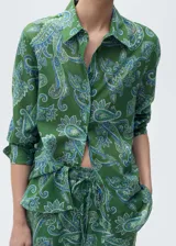 Camisa verde con estampado paisley en tonos azules, de corte recto, manga larga con puños abotonados, cuello camisero y cierre frontal con botones.