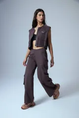 Pantalón cargo marrón de gabardina, con cierre metálico lateral, elástico en cintura trasera, recortes delanteros y bolsillos tipo cargo.