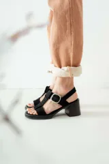 Sandalias negras de charol con tiras entrecruzadas, hebilla dorada y tacón de madera.