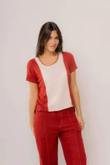 Remera blanca con panel central celeste, cuello redondo y mangas cortas. Presenta detalles de puntilla en el panel lateral.