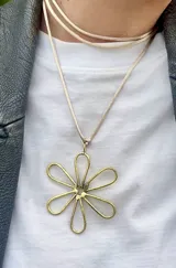 Collar con dije de margarita dorada y cordón de seda color beige.