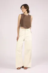 Pantalón de jean color crudo, de corte palazzo y tiro alto, con bolsillos delanteros y traseros, y costuras a la vista.