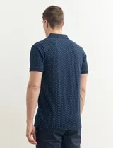 Chomba azul marino con pequeños lunares blancos, cuello clásico con botones y mangas cortas.