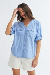 Camisa color crema de algodón con escote en V, mangas 3/4 con trabilla y dos bolsillos con solapa en el pecho.