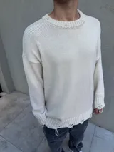 Sweater de hilo color beige, con cuello redondo y mangas largas. Presenta roturas y detalles desflecados en cuello, puños y ruedo.