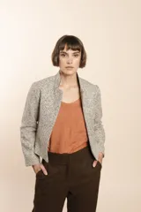 Chaqueta de sastrería color crudo con textura tweed, corte entallado, cuello mao y mangas largas.