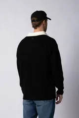 Sweater de punto verde con cuello polo color crema y bordado frontal con texto en blanco.