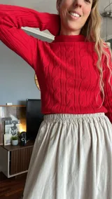 Sweater rojo de tejido de punto trenzado con cuello alto y mangas largas.
