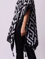 Kimono tejido con estampado geométrico en blanco y negro, ruedo con borlas y composición 100% poliéster.