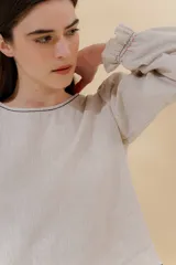 Blusa color beige de lino 100% con mangas balloon y detalle de tablón en el hombro. Tiene mangas largas con detalle de 2 pespuntes elásticos en contratono, el recurso del elástico es ideal para remangarse la manga generar más volumen. Calce recto, largo por arriba de la cadera.