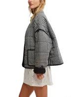 Chaqueta acolchada con estampado floral en tonos rosa y verde sobre fondo negro. Tiene cuello camisero, cierre frontal abierto, bolsillos de parche y ribete negro en contraste.