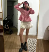 Conjunto de blusa roja y blanca a cuadros, falda blanca con volados y botas negras de plataforma.