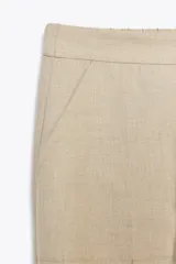 Pantalón tobillero negro de tiro medio con cintura elástica en la espalda, bolsillos delanteros y bolsillos de parche con solapa en la parte trasera. Bajo acabado con pinzas. Cierre frontal con cremallera y botón.