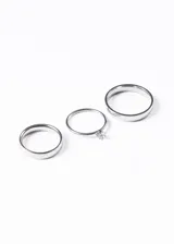 Set de tres anillos plateados: dos alianzas clásicas lisas y un cintillo con un cristal engarzado.