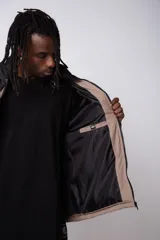 Campera puffer gris con la parte superior negra, cierre frontal y cuello alto.