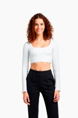 Top blanco cropped de manga larga con escote profundo, ideal para combinar con diferentes prendas.