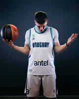 Camiseta de básquet Umbro de la selección de Uruguay, modelo alternativo. Diseño blanco con detalles celestes y azules. Incluye logo de Umbro, escudo de Uruguay y sponsor Antel en el frente.