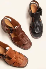 Sandalia de cuero vacuno texturado color negro, con tiras anchas y hebilla lateral. Taco ancho de madera.