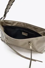 Bolso de hombro marrón de cuero sintético con dos bolsillos frontales con cremallera y tiras decorativas. El asa es trenzada y tiene herrajes metálicos.