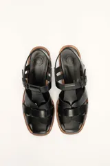 Sandalias plateadas de cuero con tiras entrecruzadas y hebilla lateral. Taco de madera de 6 cm.