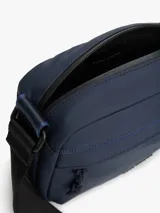 Bandolera Tommy Hilfiger azul marino con correa ajustable de tejido trenzado, cierre de cremallera, bolsillo exterior con cremallera y logo texturizado en la parte delantera.