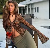 Top marrón con estampado animal print, escote en V con volados y mangas largas acampanadas. Se ata en la parte delantera con tiras.