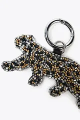 Llavero con forma de leopardo elaborado en abalorios con combinaciones de color negro, dorado y plateado.