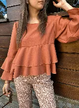 Blusa color ladrillo con corte a la cintura y volados. Mangas largas acampanadas.