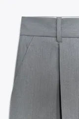 Pantalón de vestir color borgoña, de tiro alto y pierna ancha, con bolsillos laterales y cierre frontal con cremallera y ganchos metálicos.