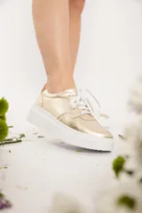 Championes dorados con cordones blancos y suela blanca con plataforma.