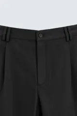 Pantalón negro de corte amplio, tipo balloon fit, con pinzas en la cintura, bolsillos laterales y traseros de ojal.