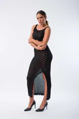 Conjunto de top y falda de tejido de punto calado color negro. El top es corto, de breteles anchos y terminación con flecos. La falda es larga, de tiro alto, corte recto y abertura lateral.