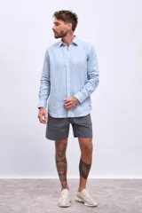 Camisa celeste de lino, de corte clásico, manga larga y cuello americano.