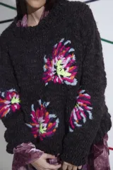 Sweater tejido y bordado a mano en lana merino, color marrón oscuro, con cuello redondo y puños ajustados. Presenta bordados florales multicolores en el frente y las mangas.