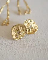 Aros tipo botón dorados con textura irregular que simula la superficie de un molusco.