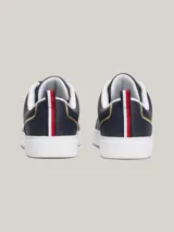 Zapatillas Tommy Hilfiger de cuero azul marino con suela blanca, cordones negros, interior blanco y detalles dorados en el talón y en el lateral.