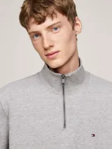 Sweater gris de felpa de mezcla de algodón aterciopelado, con cuello alto, media cremallera frontal, puños y bajo de punto canalé, cinta distintiva en el interior del cuello y logo de Tommy Hilfiger bordado en el pecho.