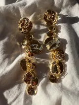 Par de aros largos dorados con piezas irregulares colgantes.