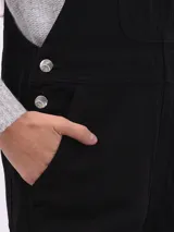 Mono enterizo negro de corte holgado con tirantes regulables y bolsillos laterales. Presenta un bolsillo tipo parche en el frente.