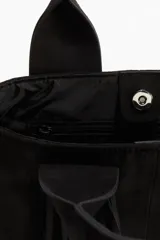 Bolso shopper negro de tejido cepillado con doble asa y flecos largos. Cuenta con cierre magnético oculto en la parte superior, compartimento interior con cierre y forro de tafeta.