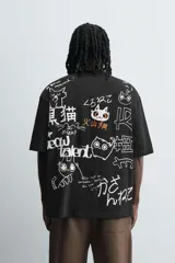 Camiseta negra de corte relaxed fit, cuello redondo y manga corta. Estampado frontal con dibujo de gato y texto en japonés.