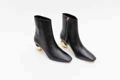 Bota de cuero color camel con punta cuadrada y cierre lateral. Tiene un taco bajo con forma de esfera dorada.