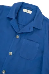 Chaqueta azul con textura seersucker, cuello con solapa, cierre con botones, bolsillo en el pecho y dos bolsillos de parche redondeados.