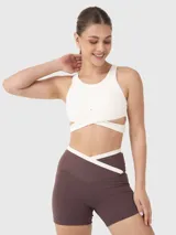 Top deportivo blanco con breteles anchos y diseño cruzado en el frente.
