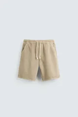 Bermuda relaxed fit color beige confeccionada en denim de algodón. Cintura elástica ajustable con cordón. Bolsillos frontales y detalle de bolsillos traseros de vivo.