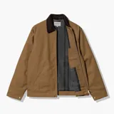 Chaqueta de estilo workwear en color tostado, con cuello de pana en contraste marrón oscuro. Cuenta con cierre frontal de cremallera, un bolsillo con cierre en el pecho y el parche con el logo de la marca en el frente.