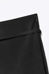 Falda pantalón blanca de tiro medio, con corte ligeramente acampanado y detalle de cinturón fino con hebilla metálica.